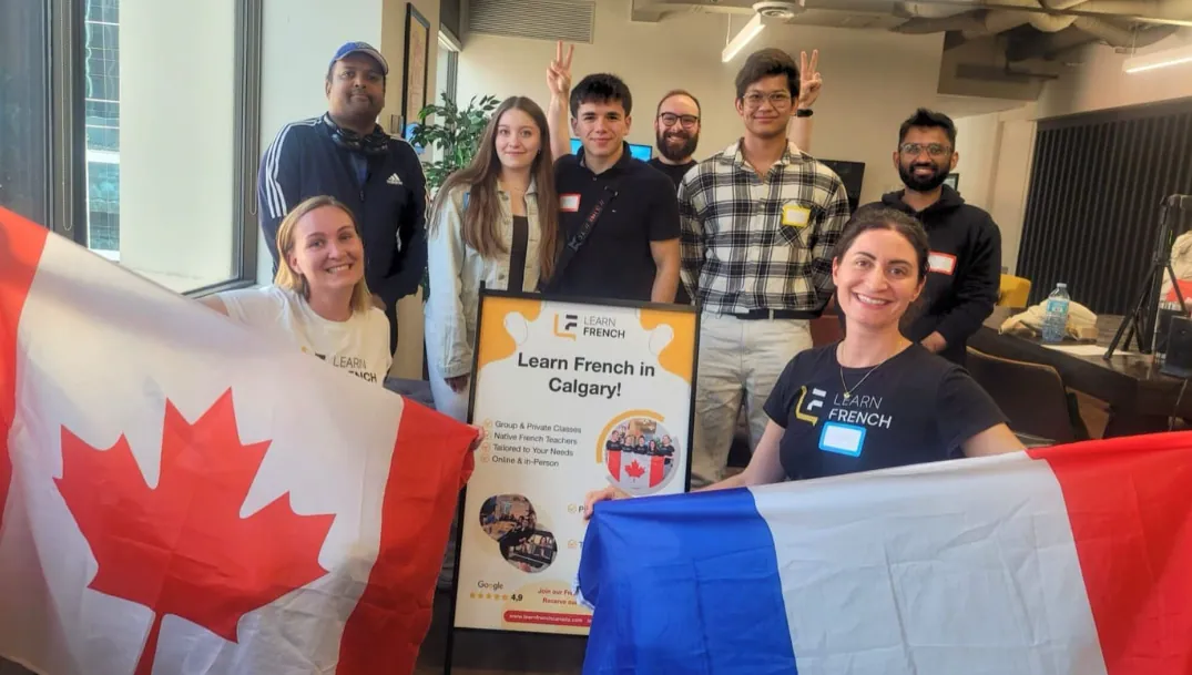 Students with Canadian and French flags around a Learn French in Calgary poster