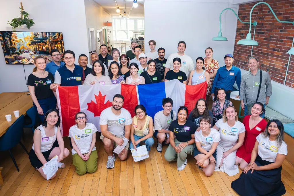 Learn French students and teachers at a summer gathering at L'Atelier in Vancouver, holding French and Canadian flags